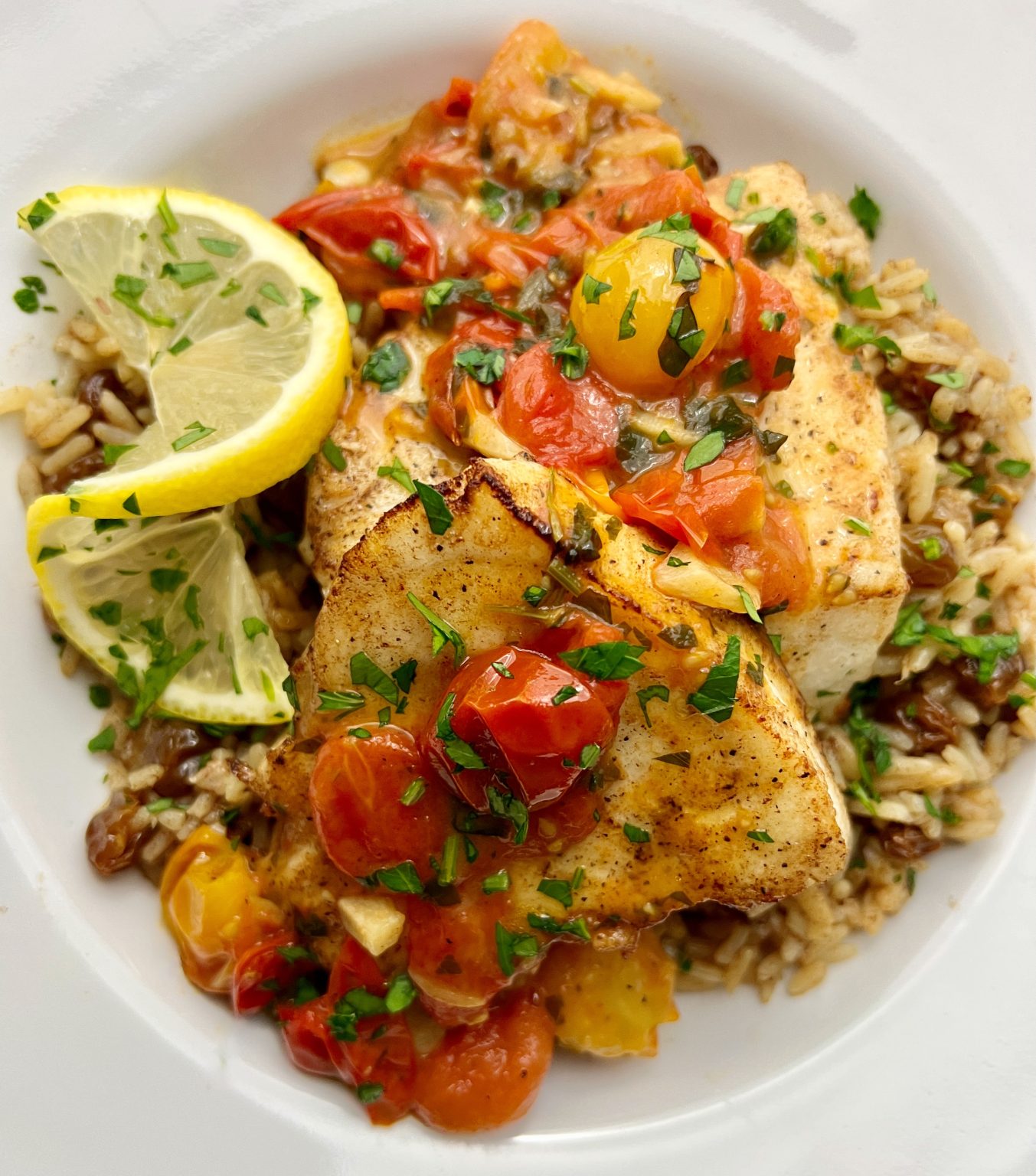 PAN SEARED CHILEAN SEA BASS OVER GOLDEN RAISIN PILAF WITH TOMATO LEMON